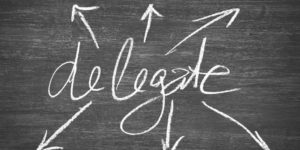 Blackboard with the word, delegate, written on it - fitting for this post about delegation in business.