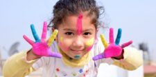 Child showing colorful paint-covered hands.