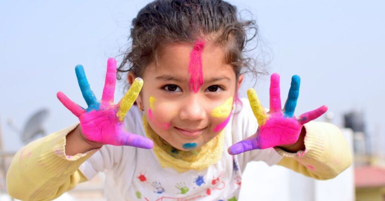 Child showing colorful paint-covered hands.