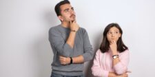 Two people looking thoughtful against a plain background.