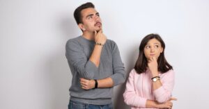 Two people looking thoughtful against a plain background.