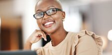 What's actually included in content writing services (and what isn't) Smiling woman wearing glasses and resting her chin on her hand while seated at a desk.