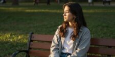 Woman sitting alone on a park bench, representing isolation linked to social media addiction.