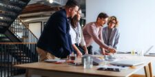 5 online marketing strategies entrepreneurs actually need Marketing team reviewing campaign ideas and planning materials around a conference table.