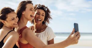 Three women taking a selfie together at the beach.