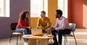 Three professionals discussing landing page strategy around a laptop in a bright, modern meeting space.