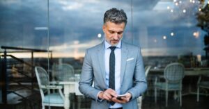 Business professional sending a text message on a smartphone, illustrating customer communication through business SMS.