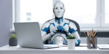 Humanoid robot sitting at an office desk with a laptop, representing AI, automation, and the future of work.