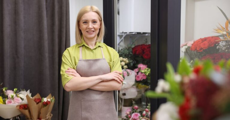 Florist standing in a flower shop surrounded by fresh bouquets, representing a small business owner using SEO to attract more customers.
