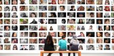 How to make WordPress multilingual for free Three people sitting on a bench viewing a large wall display filled with photos of diverse faces.