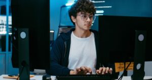 Developer working at a desktop setup with multiple monitors in a dimly lit office