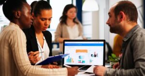 Marketing team reviewing performance data and charts on a computer during a planning meeting.