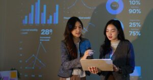 Two marketing professionals reviewing performance data in front of projected charts and analytics.