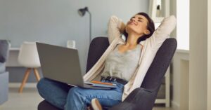 Woman relaxing in a chair with a laptop on her lap, representing the freedom and flexibility of starting a blog from home.