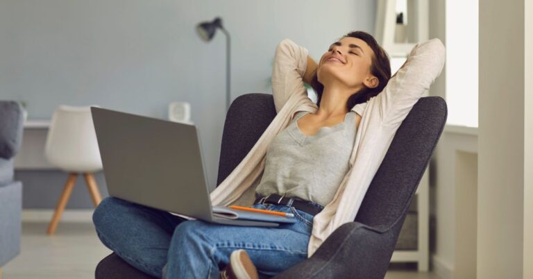 Woman relaxing in a chair with a laptop on her lap, representing the freedom and flexibility of starting a blog from home.
