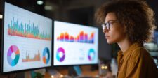 Marketing professional reviewing website traffic and performance charts on multiple computer screens.