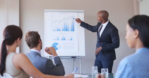 Business professional presenting charts and financial projections to a small group during a business plan presentation.