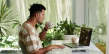 How to build an email list the easy way Man sipping coffee while working on a laptop at a bright desk surrounded by indoor plants.