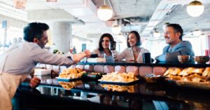Restaurant employee serving customers seated at a café counter.