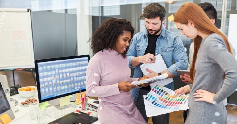 Team members reviewing design materials together in an office, representing a collaborative website accessibility review.