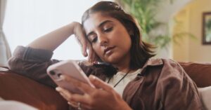 Woman scrolling on a smartphone, illustrating how people increasingly encounter news through TikTok and social media feeds.