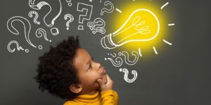 17 Characteristics Of Critical Thinkers A boy looking at a light bulb to signify thinking abilities