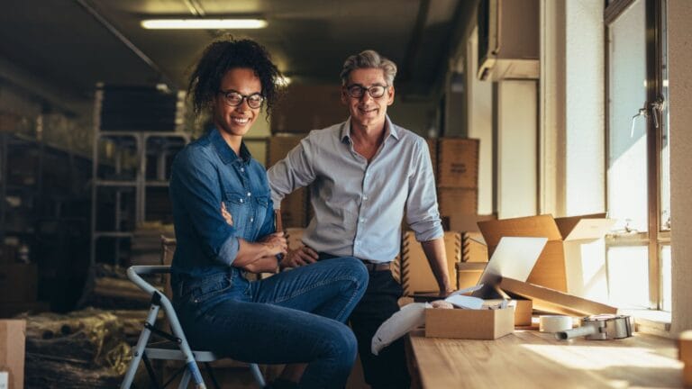 A man and woman in a dropshipping company warehouse staring at the camera.