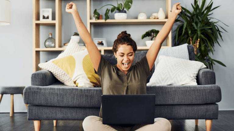 A woman looking at a laptop and very happy with arms raised — Dell Inspiron 3520 Review