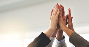 A diverse group of professionals giving a high-five, symbolizing teamwork, achievement, and collective success. This image captures the essence of collaboration and mastering the fundamentals for success.