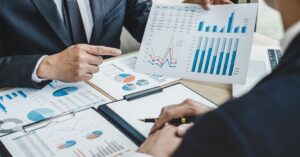 Two business professionals analyzing growth charts and graphs in a meeting, highlighting companies with blue logos driving growth.