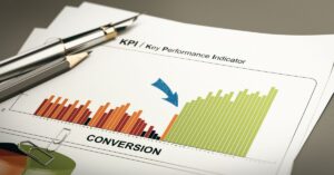 A bar graph on a document labeled 'KPI / Key Performance Indicator' shows an upward trend in conversion rates, with bars transitioning from red to green, indicating improvement. A blue arrow points to the rising green bars. A pen and paperclip rest on the document.