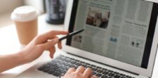 Person reading a digital newspaper on a laptop, exploring various newspaper advertising options.