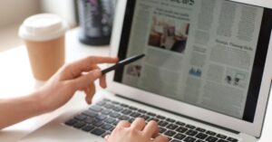 Person reading a digital newspaper on a laptop, exploring various newspaper advertising options.