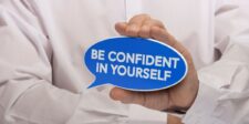 Person holding a blue speech bubble that reads 'Be Confident in Yourself,' symbolizing the theme of self-help books on confidence and self-assurance.