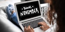 A person using a laptop displaying a Black November sale banner, featuring bold white text that reads 'Black November' on a black background with decorative elements, promoting holiday shopping deals.