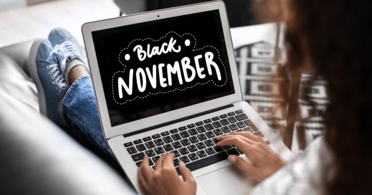 A person using a laptop displaying a Black November sale banner, featuring bold white text that reads 'Black November' on a black background with decorative elements, promoting holiday shopping deals.