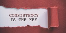 A torn red paper revealing the message 'Consistency is the Key' underneath, symbolizing the importance of steady and persistent effort. The visual emphasizes the significance of consistency, particularly in achieving long-term goals or success in business.