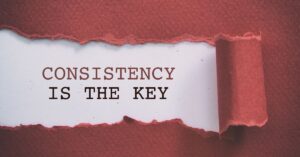 A torn red paper revealing the message 'Consistency is the Key' underneath, symbolizing the importance of steady and persistent effort. The visual emphasizes the significance of consistency, particularly in achieving long-term goals or success in business.