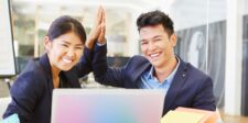 Two smiling business professionals in a modern office, high-fiving in front of a laptop, symbolizing a successful partnership, possibly representing the dynamic collaboration between a technical co-founder and another team member.