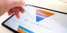 Close-up of a tablet displaying a funnel chart with various colored sections, illustrating data analysis. A hand holding a stylus interacts with the chart, highlighting the use of funnels for visualizing sales or marketing processes.