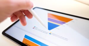 Close-up of a tablet displaying a funnel chart with various colored sections, illustrating data analysis. A hand holding a stylus interacts with the chart, highlighting the use of funnels for visualizing sales or marketing processes.