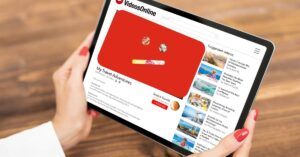 A tablet shows a travel video titled 'My Travel Adventures' demonetized on a YouTube-like platform, symbolizing the impact of YouTube demonetization on creators. The demonetization icon highlights how content creators may lose revenue even with high engagement.