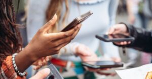 Group of professionals holding smartphones, engaging in communication and networking, representing the use of LinkedIn InMail for professional connections and outreach.