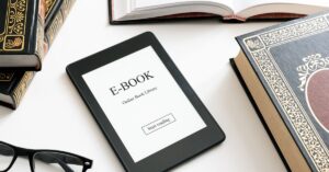 A tablet displaying an ebook cover titled "E-BOOK: Online Book Library" lies on a white surface surrounded by ornate, hardcover books, suggesting a blend of traditional and digital reading. Nearby, a pair of black glasses rests, hinting at a study or reading session. Perfect for readers interested in ebooks about business success and growth.