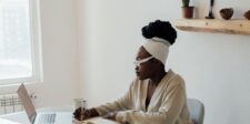 A focused woman is working independently with a laptop and notebook at her desk, illustrating the Manager of One mindset