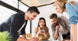 A group of four young professionals collaborating around a table, with one person leading the discussion. Optimized for the keyword 'how to lead your peers.