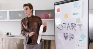 Young entrepreneur presenting a startup idea on a whiteboard with the word 'START UP' written in bold letters, showcasing innovation and the future of entrepreneurship.