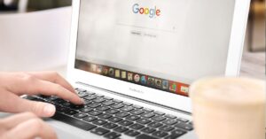 A person typing on a MacBook Air with the Google search page open, representing the concept of universal search across various platforms and data sources.