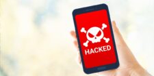 A hand holding a smartphone displaying a red warning screen with a skull and crossbones icon and the word "HACKED" in bold white letters, symbolizing a compromised Instagram account.