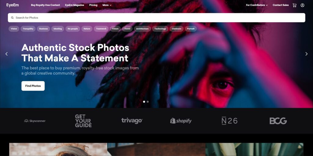 Screenshot of the EyeEm stock photo website with a headline 'Authentic Stock Photos That Make A Statement.' The homepage showcases a vibrant image with tags for categories like Vision, Business, and Nature, and features a search bar for users to explore photos.